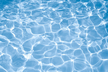 Fototapeta na wymiar Blue water surface with bright sun light reflections, water in swimming pool background