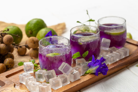 Glass of lemon juice, Pea flowers and Longan on white wooden table