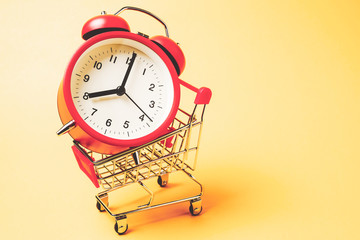 Buy time, Shopping cart with red vintage alarm clock show 8 O'clock over yellow background
