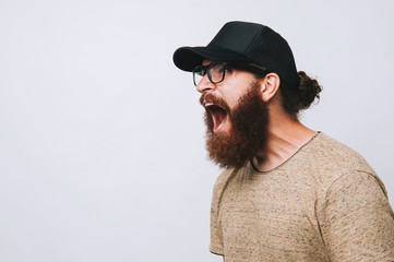 Bearded man in black hat screaming over white background