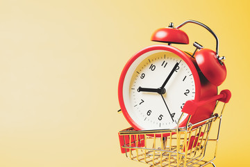 Buy time, Close-up Shopping cart with red vintage alarm clock show 8 O'clock over yellow background