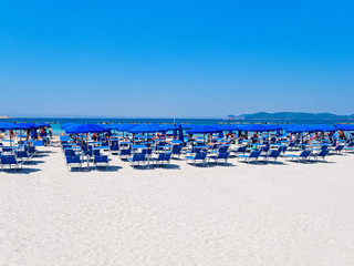 Obraz premium Alghero beach. Sea view, umbrellas and sun loungers. Sardinia, Italy.