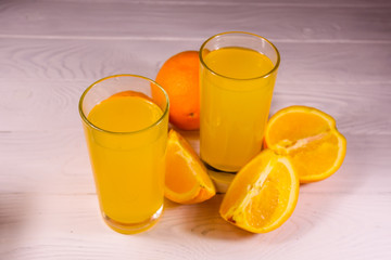 Oranges and glasses with orange juice on a wooden table