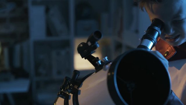 Cute superhero boy watching stars with a telescope