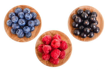 blueberry raspberry black currant in wooden bowl isolated on white background. Top view. Set or collection