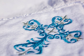 Embroidered blue cross on white carpet. Baptism. Macro