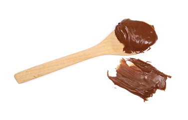 Cream chocolate spreading with wooden spoon isolated on white background, top view