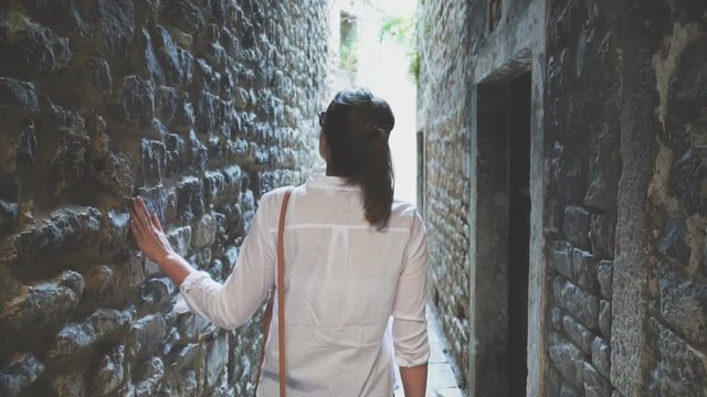 Female tourist is walking along the old narrow streets of the city.
