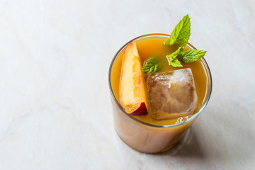 Peach Bourbon Cocktail with Peach Slice, Mint Leaves and Ice.