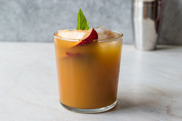Peach Bourbon Cocktail with Peach Slice, Mint Leaves and Ice.