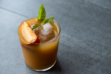 Peach Bourbon Cocktail with Peach Slice, Mint Leaves and Ice.