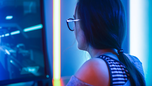 Close-up Portrait of the Beautiful Professional Gamer Girl Playing in Online Video Game, Casual Cute Geek wearing Glasses. Neon Colored Room. e-Sport Cyber Games Internet Championship Tournament.