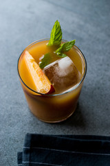 Peach Bourbon Cocktail with Peach Slice, Mint Leaves and Ice.