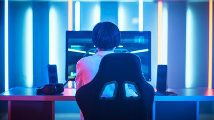 Professional Gamer Playing and Winning in First-Person Shooter Online Video Game on His Personal Computer. Room Lit by Neon Lights in Retro Arcade Style. Cyber Sport.