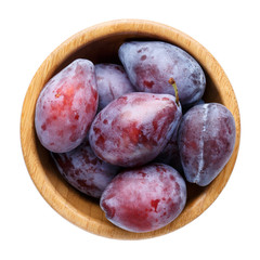 Plums in wooden bowl isolated on white. Damsons fruit. Top view.