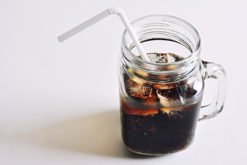 Cola with ice in glass on white background