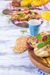 Picnic with grilled food. Sausages and corn on barbecue, shrimp, vegetables and fruits. Delicious summer lunch and plastic dishes. Top view