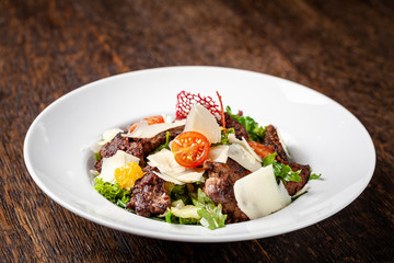 Salad from the mix of lettuce, lettuce and iceberg leaves, with cherry tomatoes, orange and grilled beef on the grill. beautiful serve in the restaurant. Copy space, selective focus