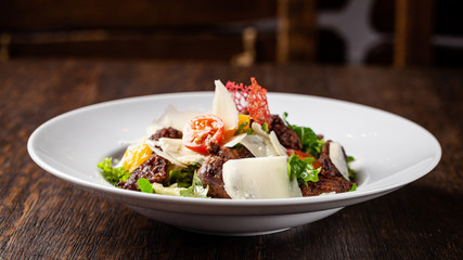 Salad from the mix of lettuce, lettuce and iceberg leaves, with cherry tomatoes, orange and grilled beef on the grill. beautiful serve in the restaurant. Copy space, selective focus