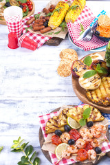 Picnic with grilled food. Different vegetables and fruits on barbecue and seafood, shrimp. Delicious summer lunch. Top view. Copy space,