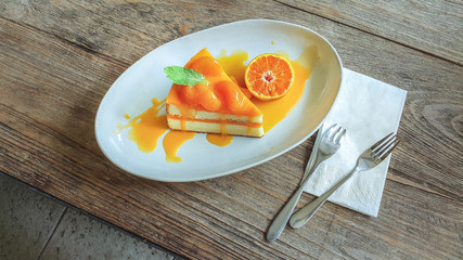 Sweet or dessert, a delicious orange cake topping with orange slices on white plate on wooden table 