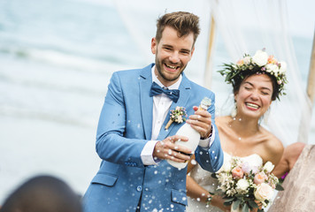 Young couple in a wedding ceremony at the beach - obrazy, fototapety, plakaty