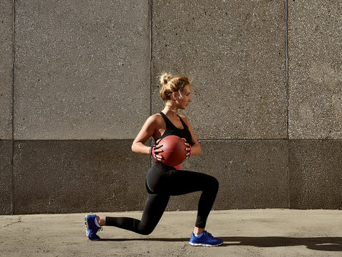 Fitness woman working out at outdoors gym using medicine ball. Sportswoman stretching outdoors with medicine ball. Copyspace for text.