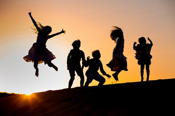 five children jump at sunset