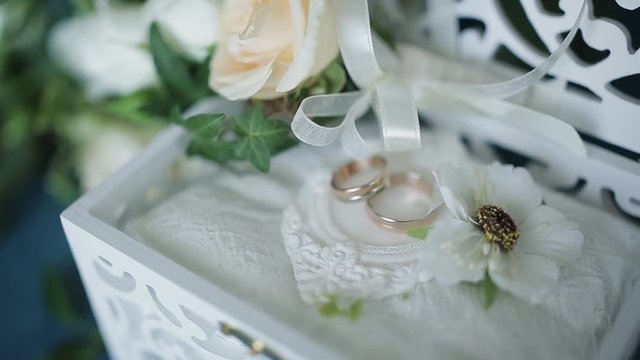 Wedding concept. Wedding rings in a wooden box handmade, surrounded by flowers on a turquoise background.