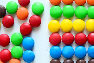 Background of colorful button-shaped candies coated chocolate sweets on white background.