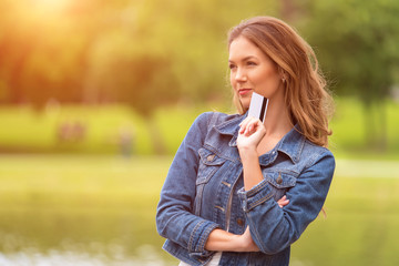 Young woman holding a credit card in park