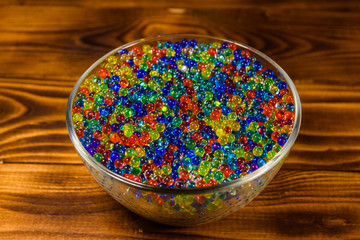Multicolored hydrogel balls in a glass bowl on wooden table
