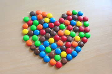 Background of Colorful button-shaped chocolates candy in the love shape on isolate