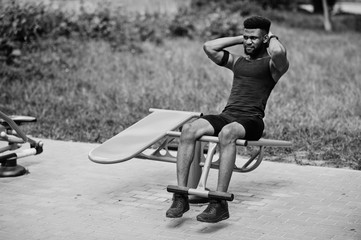 African american male athlete sport man with running sports arm case for mobile phone, doing exercises on the street workout simulators.
