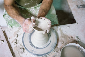 Fototapeta na wymiar Ceramic dishes in working process. Creating ceramic pieces. Tradicional ceramic factory in spain. man working with traditional potter's wheel