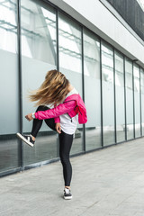 Obraz premium young stylish woman with obscured face by hair dancing at urban street