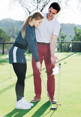 Obraz premium Man teaches woman base golf hit