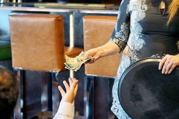 The hand of the waitress takes the tip. The waiter girl receives a tip from the client at the hotel...