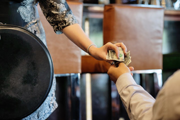 The hand of the waitress takes the tip. The waiter girl receives a tip from the client at the hotel bar. A bartender woman is happy to receive a tip at work. The concept of service.