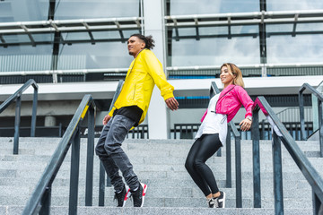 low angle view of young multiethnic couple dancing on stairs at urban street