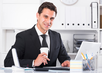 Smiling manager working on laptop