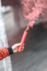 cropped image of young woman holding red smoke bomb at city street