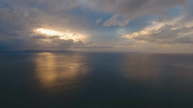 Sunset over the sea. Aerial view: Sunset over the sea in the background orange sky and islands. Fly over the ocean in sunset time. Travel concept. Nothing but sky, clouds and water. Beautiful serene