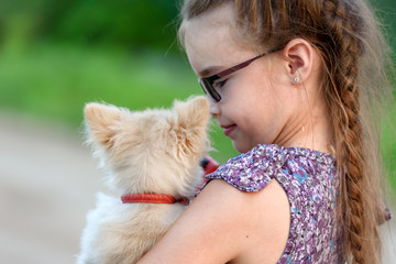 A girl with a little dog on her shoulder, rear view