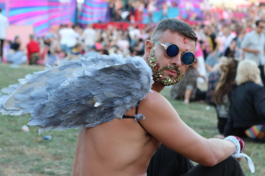 Sexy man with wings and glitter beard in music festival 