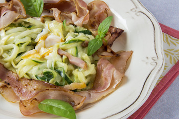 Scrambled eggs with zucchini, carbonara sauce and bacon