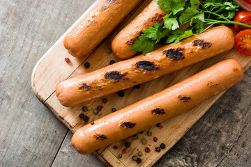 Grilled sausages and ketchup on wooden table