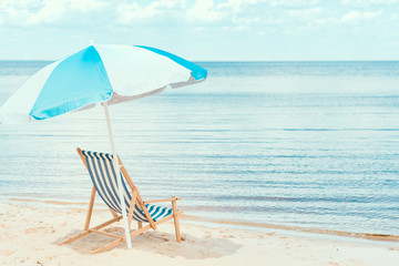 sun umbrella and beach chair on sandy shore near the sea