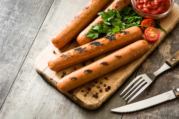 Grilled sausages and ketchup on wooden table
