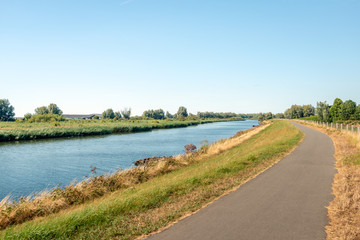 Narrow bike path next to a wide creek in a nature reserve